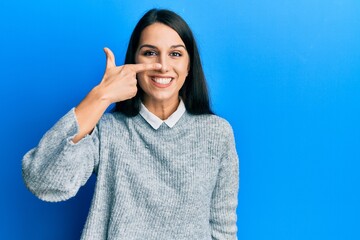 Young hispanic woman wearing casual clothes pointing with hand finger to face and nose, smiling cheerful. beauty concept