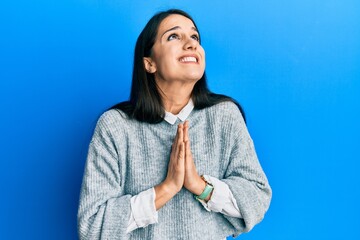 Young hispanic woman wearing casual clothes begging and praying with hands together with hope...