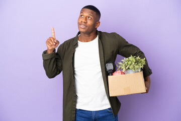 Latin man making a move while picking up a box full of things pointing up a great idea