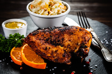 Stuffed chicken breast and coleslaw on wooden table
