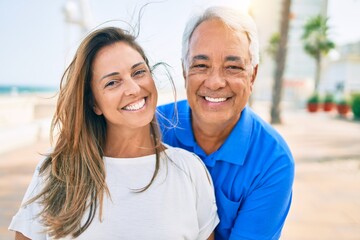 Obraz premium Middle age hispanic couple smiling happy hugging at the promenade.