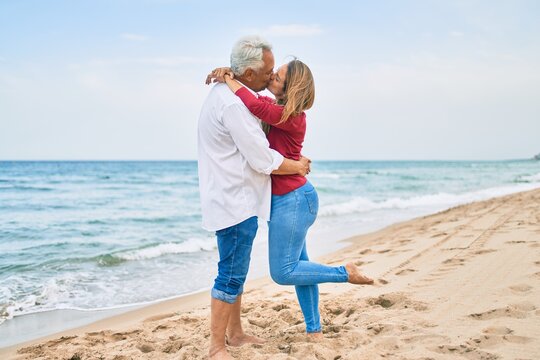 Middle age hispanic couple kissing and hugging at the beach