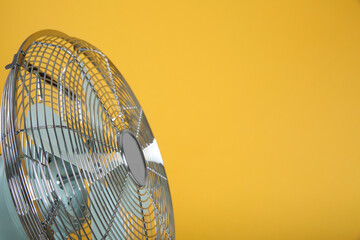 Modern electric fan on yellow background, closeup. Space for text