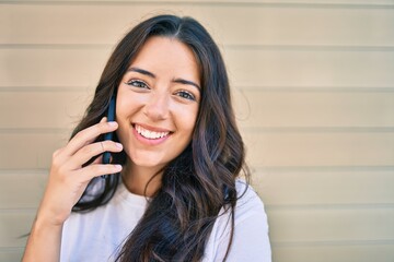 Young hispanic woman smiling happy talking on the smartphone at the city.