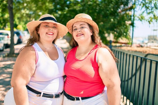 Two plus size overweight sisters twins women hugging together outdoors