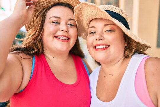 Two plus size overweight sisters twins women hugging together outdoors