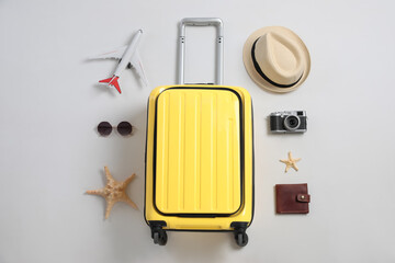 Flat lay composition with suitcase and travel accessories on grey background. Summer vacation