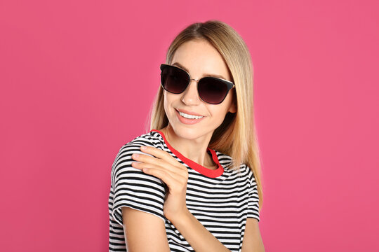 Beautiful woman in stylish sunglasses on pink background