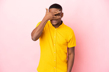 Young latin man isolated on pink background covering eyes by hands and smiling