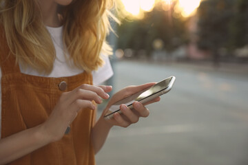 Woman ordering taxi with smartphone on city street, closeup