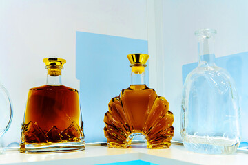 Bottles with cognac in beautiful, glass bottles. Shelf with alcohol on a light background. Close-up