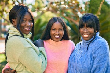 Three african american friends smiling happy hugging at the park.