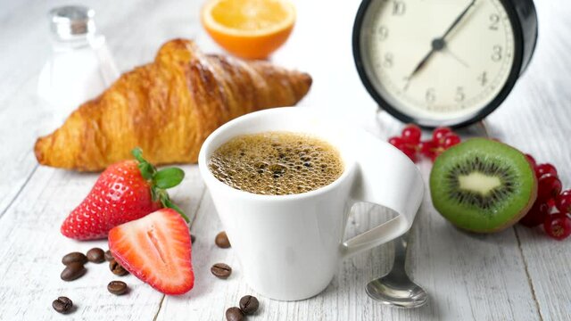 coffee cup with fruit, croissant and alarm clock