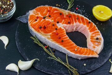 Raw salmon steak with spices on black slate