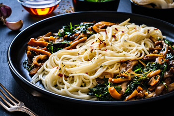 Asian food - fried soy sauce oyster mushrooms with noodles on black stone
