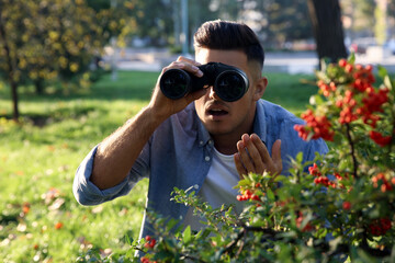 Jealous man with binoculars spying on ex girlfriend in park