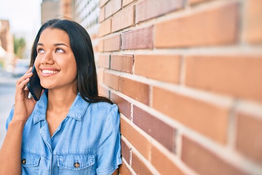 Young latin girl smiling happy talking on the smartphone at the city.