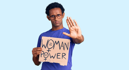 African handsome man holding woman power banner with open hand doing stop sign with serious and confident expression, defense gesture