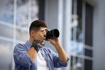 Fototapeta na wymiar Photographer taking picture with professional camera on city street