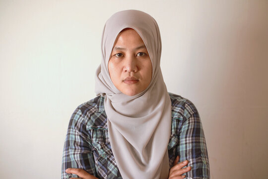 Asian muslim woman wearing hijab looking at camera with neutral expression, diverse people portrait