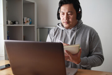 Asian man having video teleconference on his laptop at home, online learning or working from home