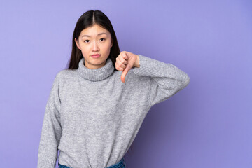Fototapeta premium Young asian woman over isolated background showing thumb down with negative expression
