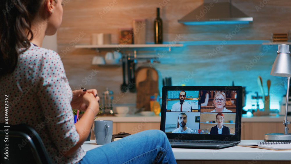 Poster freelancer working remotely discussing with partners online using laptop sitting in the kitchen at n