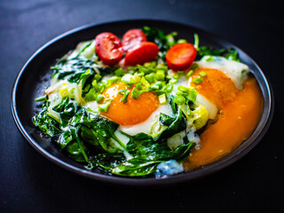Sunny side up eggs with spinach on wooden table