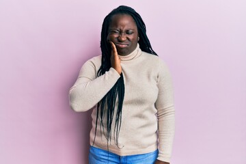 Fototapeta premium Young black woman with braids wearing casual winter sweater touching mouth with hand with painful expression because of toothache or dental illness on teeth. dentist