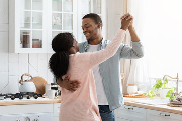 Passionate african american couple dancing in light kitchen interior, having fun together