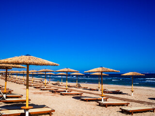 Empty deckchairs and parasols on empty beach
