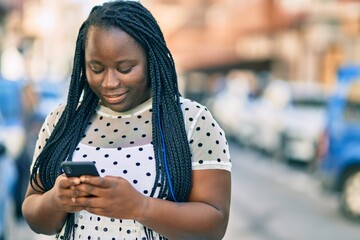 Young african american woman smiling happy using smartphone at the city.