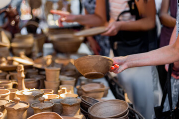 Customer buying decorative ceramic plates on street market, small business, outdoor street sale in...