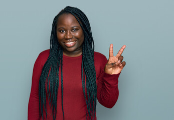 Young black woman with braids wearing casual clothes smiling with happy face winking at the camera...