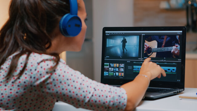 Videographer working on laptop from home, editing video and audio footage at night. Woman content creator using professional device modern technology network wireless processing film montage.