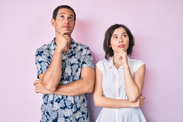 Beautiful couple wearing casual clothes with hand on chin thinking about question, pensive expression. smiling with thoughtful face. doubt concept.