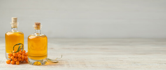 Natural sea buckthorn oil and fresh berries on white wooden table, space for text. Banner design