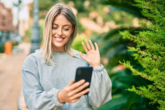 Young blonde girl smiling happy doing video call using smartphone at the park