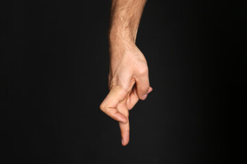 Man imitating walk with hand on black background, closeup. Finger gesture