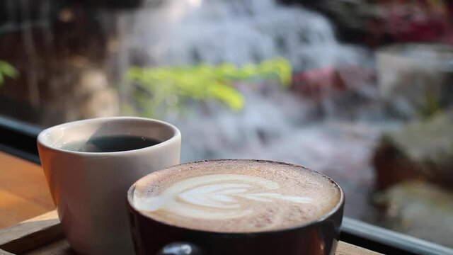 Morning cup of coffee latte in waterfall garden view, stock footage