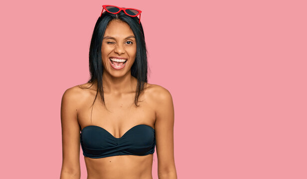 Young african american woman wearing bikini winking looking at the camera with sexy expression, cheerful and happy face.