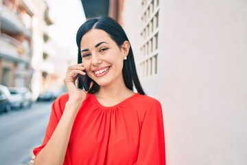 Young latin girl smiling happy talking on the smartphone at the city.