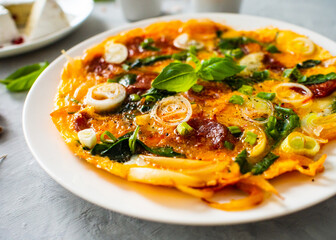 Delicious breakfast - scrambled eggs with onion and chorizo on wooden table