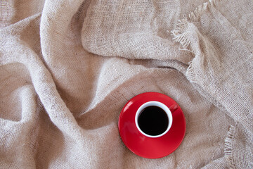赤いコーヒーカップにいれたコーヒー（麻布の背景）	
