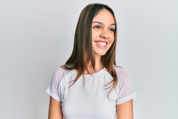 Fototapeta premium Young brunette woman wearing casual white t shirt looking to side, relax profile pose with natural face and confident smile.
