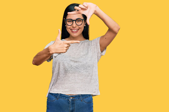 Beautiful young woman wearing casual clothes and glasses smiling making frame with hands and fingers with happy face. creativity and photography concept.