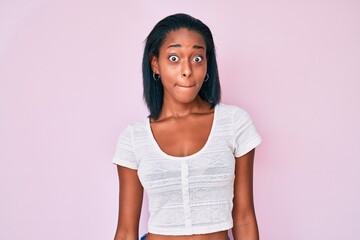 Young african american woman wearing casual clothes puffing cheeks with funny face. mouth inflated with air, crazy expression.
