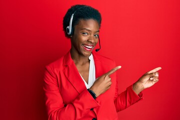 Young african american girl wearing call center agent headset smiling and looking at the camera...