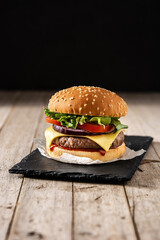 Cheeseburger with beef,tomato, lettuce and onion on wooden table - obrazy, fototapety, plakaty
