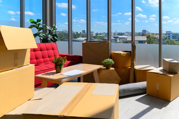 cardboard boxes stacked, plants, comfortable couch near big window inside of modern living room in new house, celebrating moving to new home concept, no people